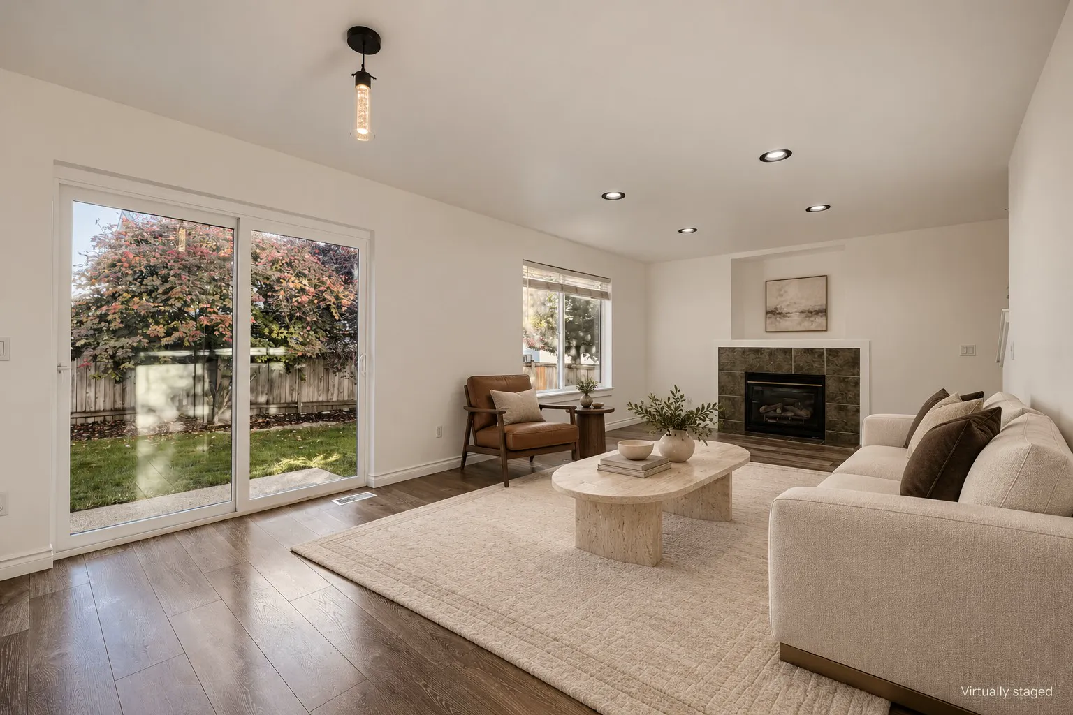Family room with gas fireplace and slider to the patio, virtually staged